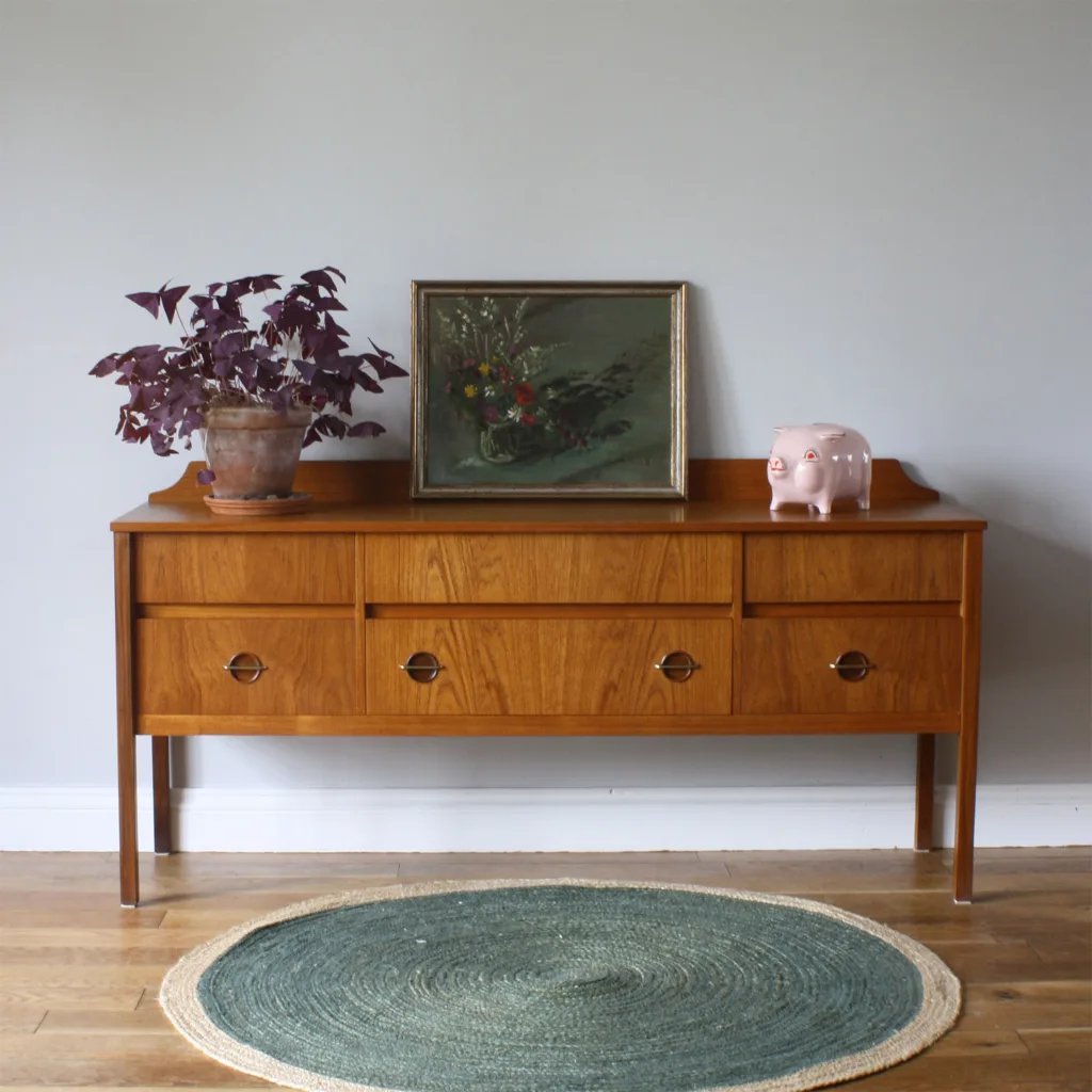 With a stately design that's neither too traditional nor too mid century, this is a versatile vintage piece that can serve downstairs as a sideboard or console table, or upstairs as a drawer chest or dressing table. Thoughtfully designed with elegant details like the round, lower handles and the contoured trim at the back, and beautifully made with fine wood (the tone and grain is superb) and expert construction, it's British and dates from the early 1960s. We love furniture that straddles generations and styles, a sign of classic, timeless design, and this will happily mix with modern pieces, midcentury design, antiques of different wood types or more traditional home styling.

We can arrange fast UK delivery!