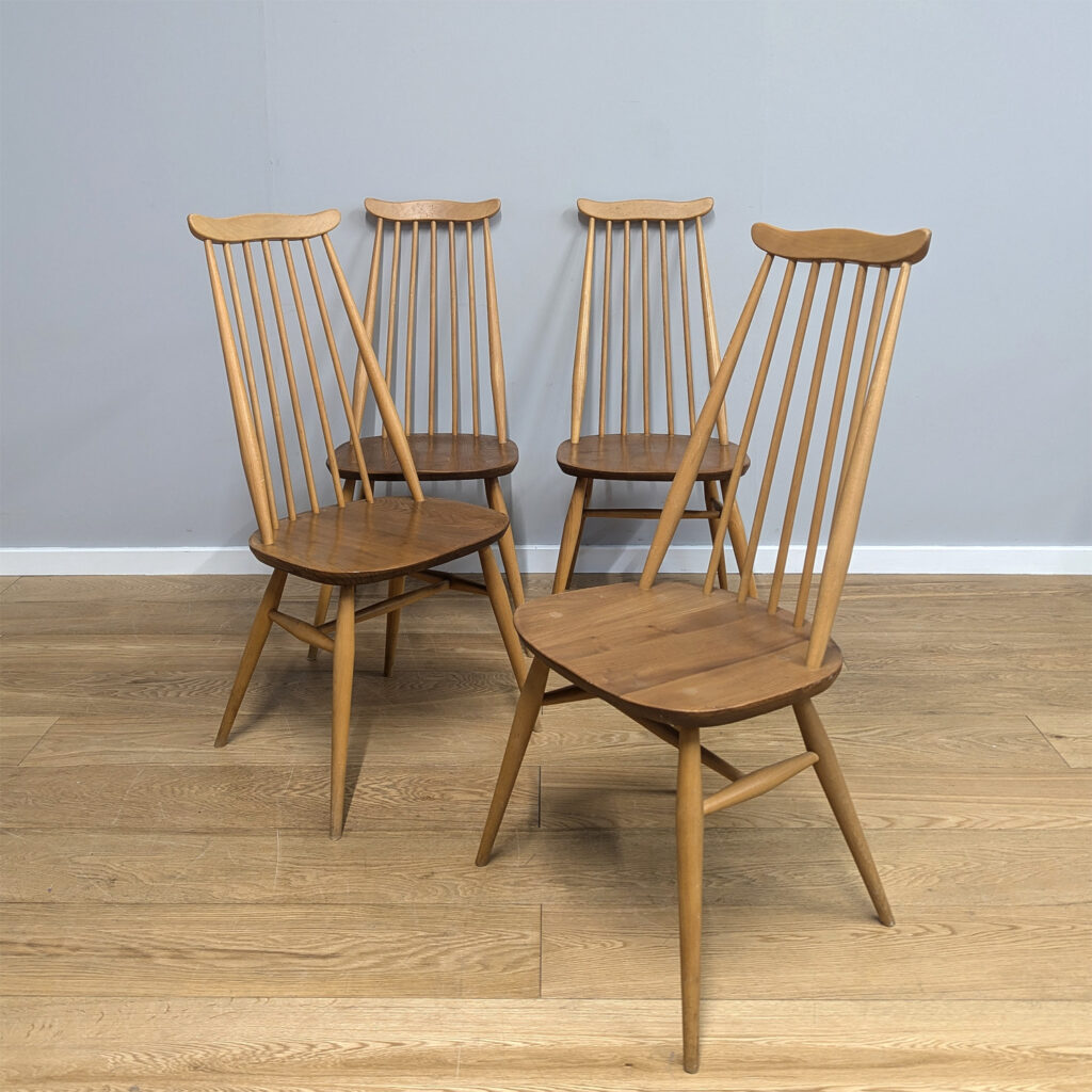 Ercol's vintage Goldsmith chairs are among some of their most popular with an appeal that endures. Tall and elegant with the signature 'moustache' top, this set of four come in their original finish and date from the 1970s. Constructed with beech legs and English elm seats, they are solid wood, sturdy and expertly crafted as you would expect from Ercol. This set would look just as at home around a rustic country kitchen table as they would a mid century inspired dining room.