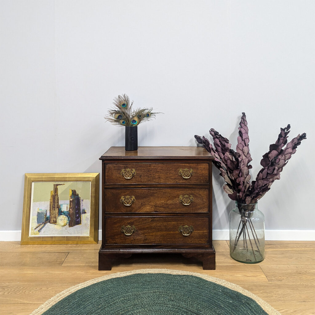 A really sweet, antique, late Georgian chest of drawers in beautiful, richly toned mahogany. We love the neat proportions of this piece. It would make an ideal accompanying piece to a large chest of drawers or the height means that you could add a freestanding mirror on top and use it as a vanity stand. With three graduated drawers, there's plentiful storage. The round, hanging brass handles are original and it sits on bracket feet. This is a very old piece that does come a little faded and bruised - do browse through our photos for a good sense of this - but we love the minor imperfections of the antique timber and the history it holds. It's very well-made, has already proved its longevity and is full of old-fashioned character.