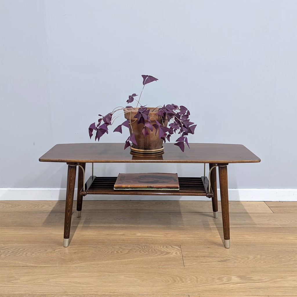 A smashing, little vintage coffee table here, bringing the retro vibes. The capped, splayed legs are an 'atomic' nod synonymous with sixties design but it's the magazine shelf below held in place by shaped metal arms that is the standout feature. It comes in its original, high shine finish so there are superficial scuffs here and there, but regardless a cracking, rather kitsch piece with more compact proportions than a regular coffee table.