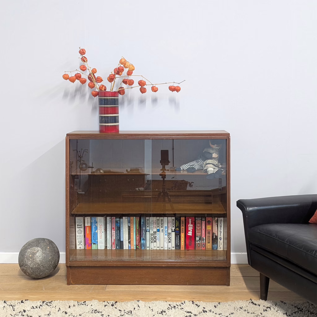 Lots of midcentury, glass front book shelves pass through our doors, their appeal enduring, but this one, designed by VB Wilkins for E Gomme, is a cut above in our view. Designed as part of his 1950's Brandon range which continued production into the late sixties, unusually this is crafted in teak rather than the pale oak more commonly seen on Brandon pieces. This piece is in solid, vintage order order. Its the angles and the thoughtful craftsmanship that elevates it. We love how the angled sides and front that pour down from the top and the cut-away at the base.

&nbsp;

Free Local Delivery / Fast UK Delivery / £20 Off If You Collect