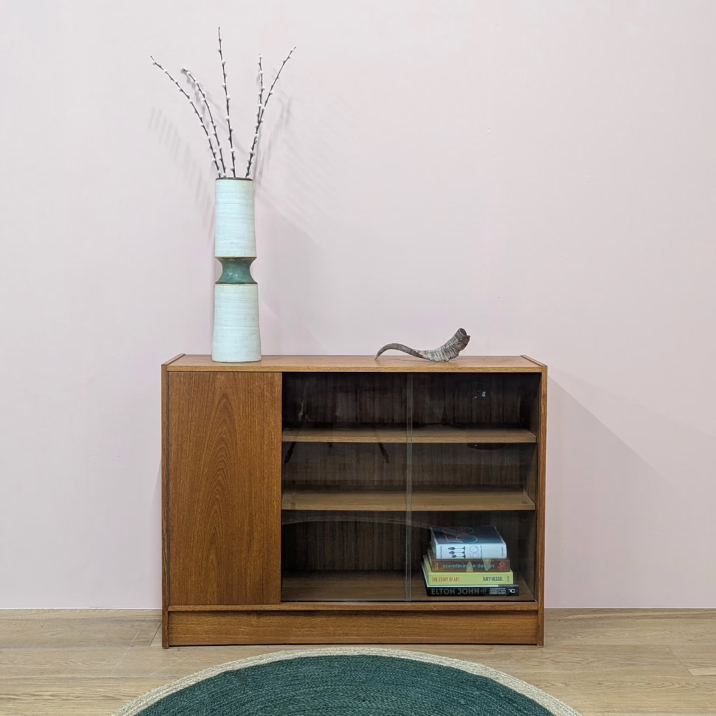 On show and hidden storage in one useful, vintage cabinet. Part bookcase / display cabinet, part cupboard, this is a really handy, domestic piece, solidly made and in cracking order. It dates from the 1970s with a design that’s neutral, practical and won’t compete with other furniture. We love that even the cupboard handle is hidden making it really streamlined. With a shallow depth it can tuck quietly against the wall.

&nbsp;

Free Local Delivery / Fast UK Delivery / £20 Off If You Collect

&nbsp;
